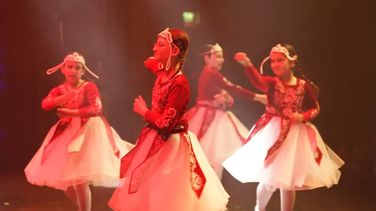 Meisjes in rode jurken met witte tule rokken dansen in rood podiumlicht