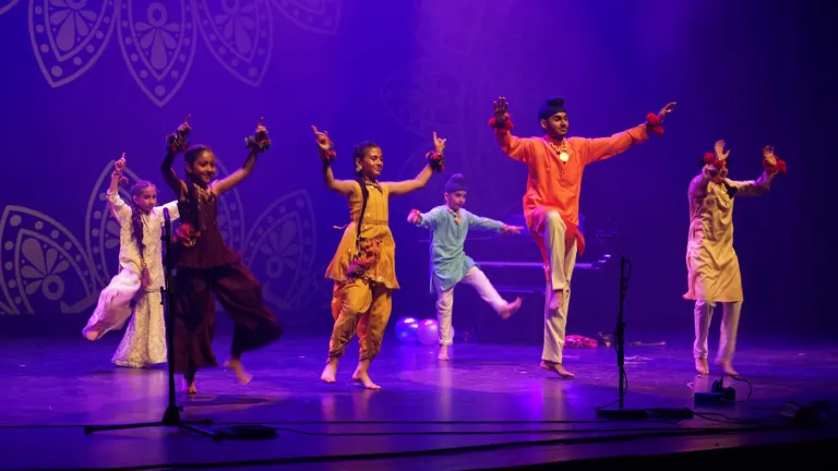 Dansers in kleurrijke klederdracht dansen voor een decor met sierpatronen