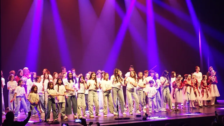 Een grote groep jongeren danst op het podium onder paarse lichtbundels tijdens editie 2026