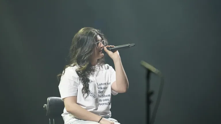 Een meisje in een wit T-shirt zingt zittend in haar microfoon