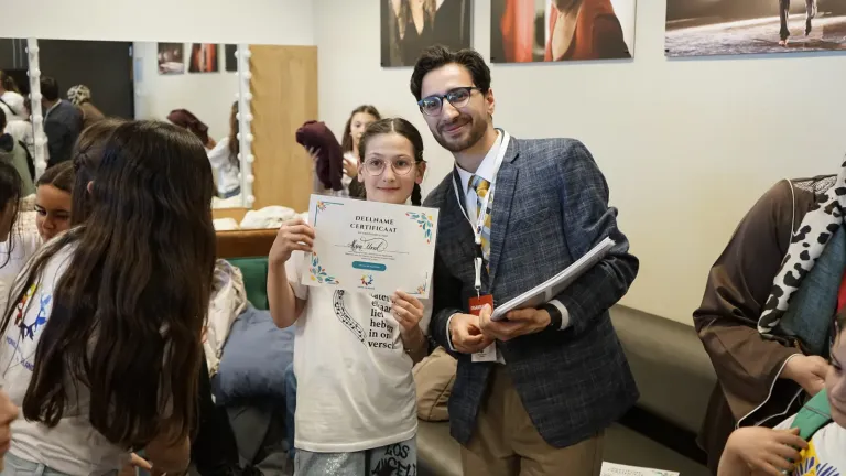 Een deelnemer laat trots een certificaat zien naast een organisator