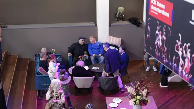Bovenaanzicht van de foyer waar bezoekers in gesprek zijn in een loungehoek