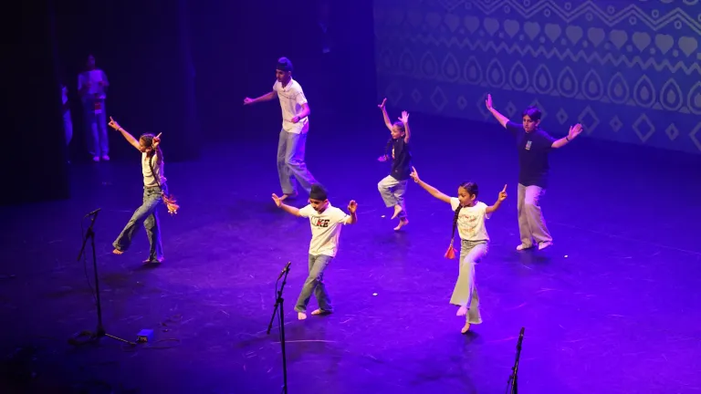 Een groep jongeren danst op het podium in paars licht