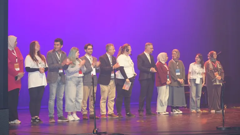 Deelnemers en organisatoren staan naast elkaar op het podium