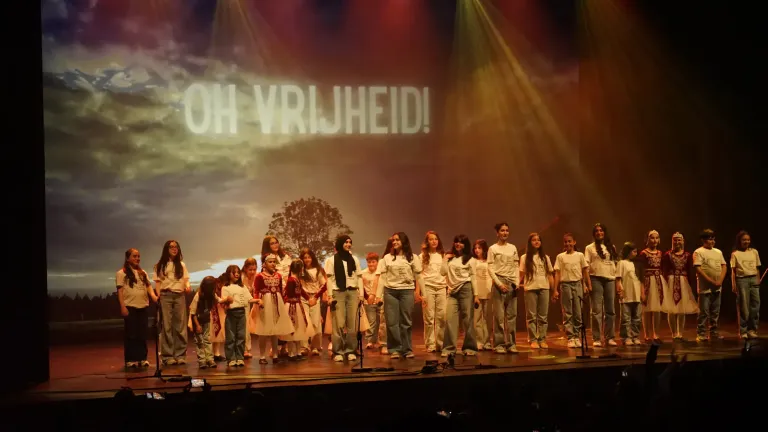 Jongeren staan in een rij voor een scherm met de woorden 'Oh vrijheid'