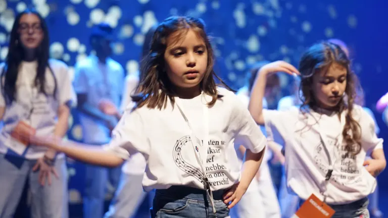 Twee meisjes in witte T-shirts dansen op het podium in blauw licht