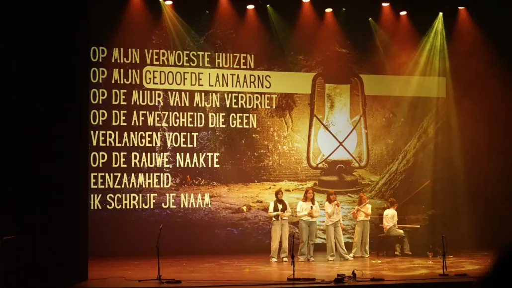 Een gedicht met een brandende lantaarn op het scherm boven jongeren op het podium