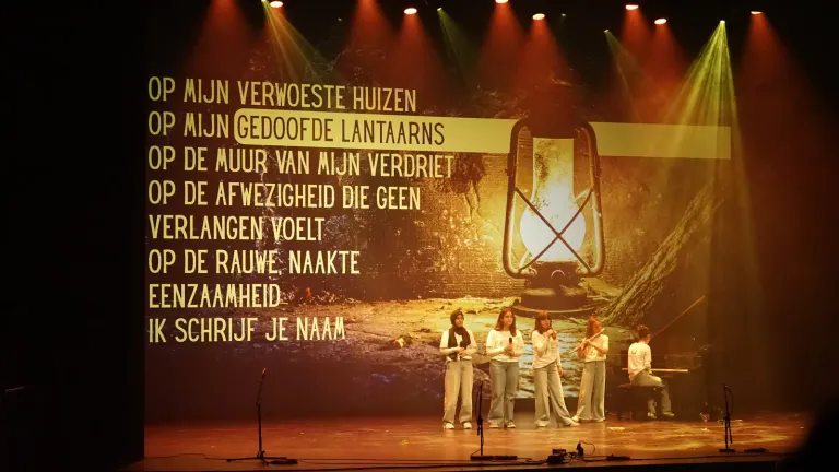Een gedicht met een brandende lantaarn op het scherm boven jongeren op het podium